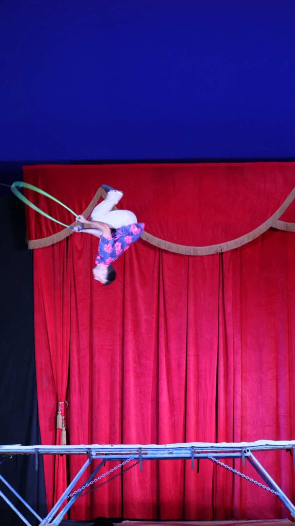 Backflip on trampoline at circus with hula hoop